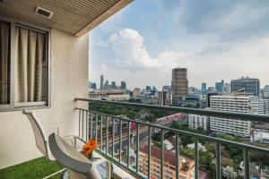 a balcony with two chairs and a view of a city at Evergreen Place Siam by UHG in Bangkok