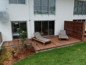 - deux chaises sur une terrasse en bois devant une maison dans l'établissement Le Pacifik Kone, à Koné