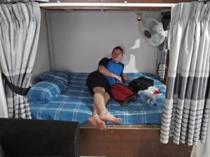 una donna seduta su un letto in una stanza di Kingfisher Hostel a Anuradhapura