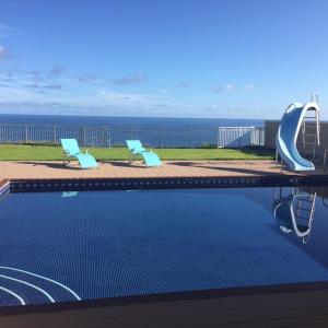 einen Pool mit zwei Stühlen und einer Rutsche in der Unterkunft Oceanfront Home with PRIVATE POOL in Tamuning