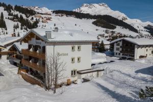 budynek w śniegu z górą w tle w obiekcie Hotel - Pension Fortuna w Lech am Arlberg