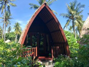 Cabaña pequeña en medio de un jardín con palmeras en Meno Madia Bungalows, en Gili Meno