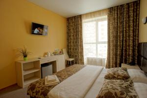 a hotel room with a bed and a desk and a window at Hotel Marton Osharskaya in Nizhny Novgorod