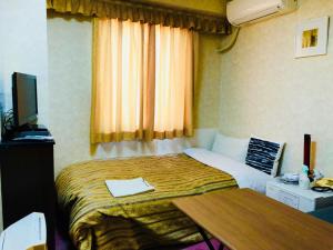 a bedroom with a bed with a desk and a television at Business Green Hotel Hino in Hino +23 photos