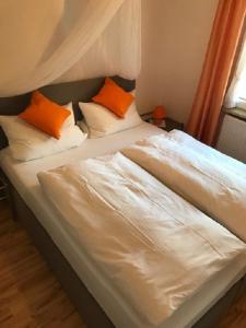 2 Betten mit orangefarbenen und weißen Kissen im Schlafzimmer in der Unterkunft Ferienwohnung Gruß aus Partenkirchen in Garmisch-Partenkirchen