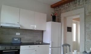 een keuken met witte kasten en een witte koelkast bij Apartment Nada in Rogoznica +29 foto's