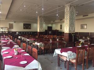 a dining room with tables and chairs with red table cloth at Hotel Glitz Jaipur in Jaipur