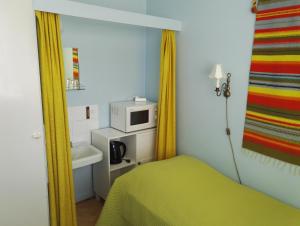 a small room with a bed and a microwave at Guesthouse Outa in Rovaniemi