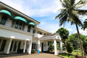 un edificio con una palmera delante de él en Villa Sri Manganti en Yakarta