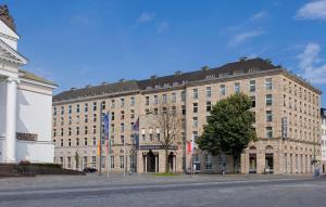 ein großes Braungebäude mit einem Baum davor in der Unterkunft Wyndham Duisburger Hof in Duisburg