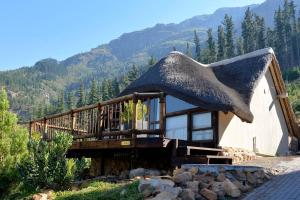 a house with a thatched roof with mountains in the background at Chamonix in Franschhoek