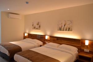 three beds in a hotel room with lights on the wall at Gold Boutique Hotel in Seremban +16 photos
