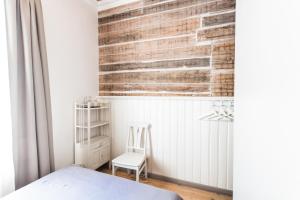 a bedroom with white walls and a white bed and a chair at Meke in Mustkalni