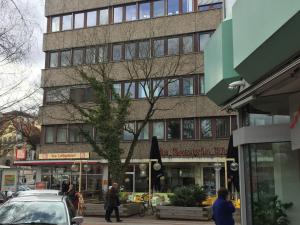 un edificio alto con gente caminando delante de él en Pension QMT Reutlingen, en Reutlingen