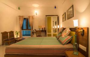 a living room with a bed, chair, and table at The Coral Court Homestay in Agra