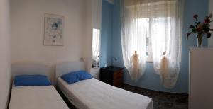 two beds in a room with two windows at Casa Luca in Silvi Marina