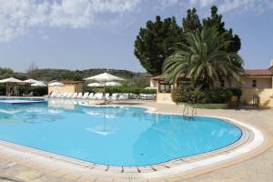 a large blue swimming pool with chairs and trees at Green Garden Club in Briatico