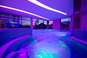 a room with a pool with purple and green lights at Imola Hotel Platán - Adults Only in Eger +78 photos