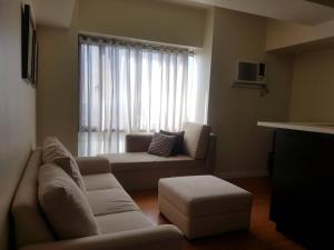 Una sala de estar con un sofá y una ventana. en Eton Baypark, en Manila