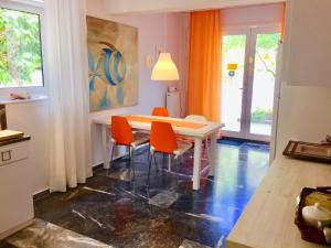 a dining room with a table and orange chairs at Flower Garden in Mati