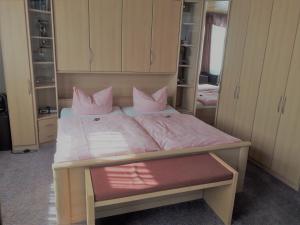 a bedroom with a bed with pink pillows on it at Deutsches Haus Munster in Munster im Heidekreis