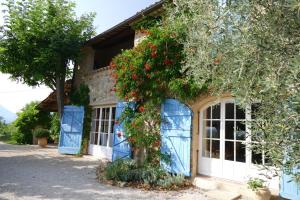 Una casa con puertas azules y flores rojas. en Chambre d'Hôtes le Jas des Sagnières, en Sigoyer
