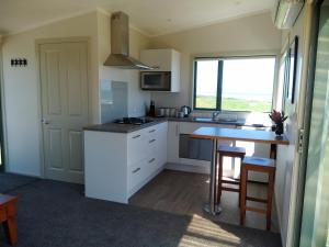 a kitchen with a counter and a table and a window at Okari Cottage in Cape Foulwind
