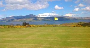 a golf course with a yellow flag on a green field at The Carradale Hotel in Carradale