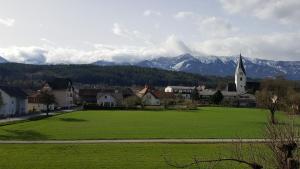 a green field with a church and mountains in the background at Gastehaus Melcher in Villach