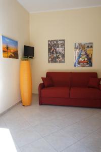 een woonkamer met een rode bank en een aantal foto's bij Casa Vacanza il Ciliegio in Noto