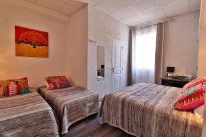 a hotel room with two beds and a window at Hôtel le Chardon Bleu in Sainte-Maxime