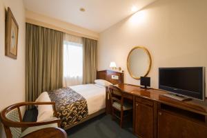 a hotel room with a bed and a desk with a television at Dukes Hotel Nakasu in Fukuoka +26 photos