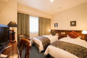 Una habitación de hotel con dos camas y un escritorio. en Dukes Hotel Nakasu, en Fukuoka