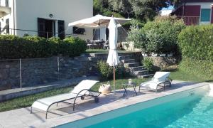 two chairs and an umbrella next to a swimming pool at il corbezzolo - Suite in Levanto