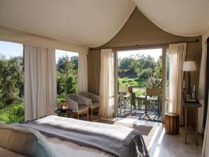 Simbavati River Lodge في محمية صيد تيمبافاتي: غرفة نوم بسرير وباب زجاجي منزلق