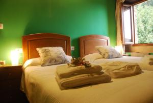 Habitación verde con 2 camas y toallas. en Isabel Artemis ES, en San Tirso de Abres