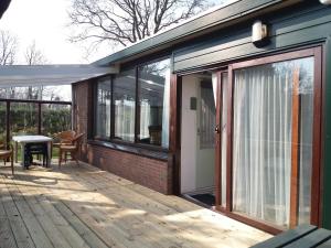 una puerta corredera de cristal en una terraza con mesa en Recreatie Bungalow Eureka, en Sint Maartenszee