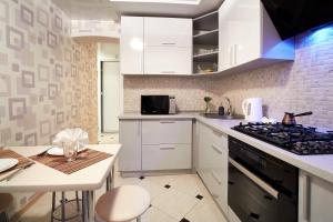 a kitchen with white cabinets and a stove top oven at PaulMarie Apartments on Kozhara in Gomel