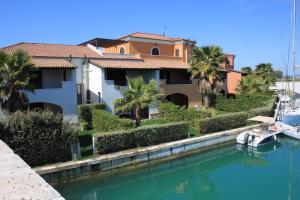 a house with palm trees and a boat in the water at Marinagri Resort in Policoro