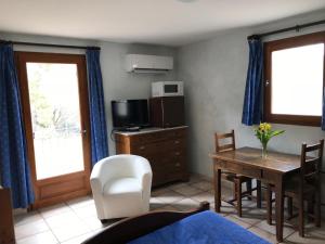 a living room with a dining room table and a tv at Chambre: une fenêtre sur le Ventoux in Plaisians