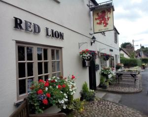 Un bâtiment en lion rouge avec des fleurs devant lui dans l'établissement Red Lion Inn, à Little Budworth