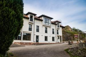 a white house with black windows on a street at Hotel Montañas de Covadonga in Cangas de Onís