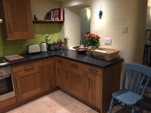 a kitchen with wooden cabinets and a counter with a blue chair at Rock View in Froggatt +23 photos