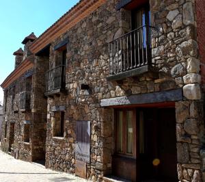 a stone building with a balcony on the side of it at Estrella rural casa rural en la Sierra de Madrid in Buitrago del Lozoya