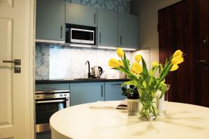 a kitchen with a table with yellow flowers in a vase at JessApart – Ochota Apartments in Warsaw