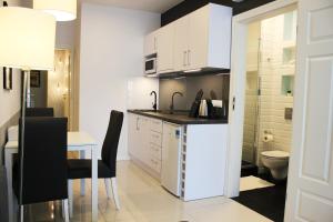 kuchnia z białymi szafkami, stołem i toaletą w obiekcie JessApart – Ochota Apartments w Warszawie
