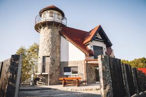 ein Haus mit einem Leuchtturm neben einem Zaun in der Unterkunft Villa Tower Nad Jeziorem Nyskim in Skorochow