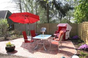 a patio with a table and chairs and an umbrella at Hus Wattkieker 7b in Husum