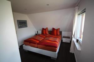 ein Schlafzimmer mit einem Bett mit roten Kissen in der Unterkunft Hus Wattkieker 7b in Husum