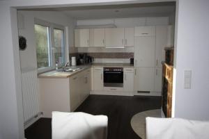 a kitchen with white cabinets and a sink at Hus Wattkieker 7b in Husum